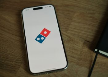 A white cell phone with a blue and red domino logo on it