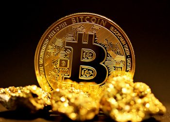 a bitcoin sitting on top of a pile of gold nuggets