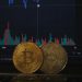 Gold Bitcoin and silver Ethereum coins resting on a laptop keyboard before a trading chart
