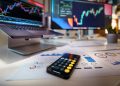 smartphone calculator on desk with financial charts behind
