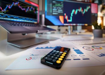 smartphone calculator on desk with financial charts behind