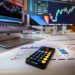 smartphone calculator on desk with financial charts behind